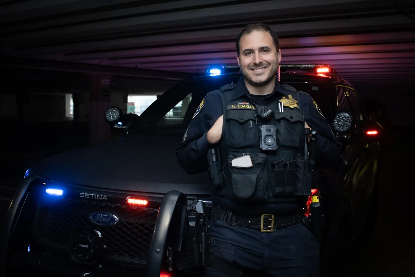 William Ojakian, LOC8 founder and sworn law enforcement officer, in uniform beside a patrol vehicle